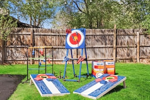 A backyard with a wooden fence, two bean bags, a swing set, and a target board. - Dog-Friendly Arvada Home with Fire Pit, 18 Min to Red Rocks & Near Denver (Arvada)