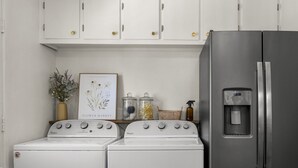 A kitchen with a stainless steel refrigerator, two Whirlpool washers, and a framed botanical print on the wall. - Dog-Friendly Arvada Home with Fire Pit, 18 Min to Red Rocks & Near Denver (Arvada)