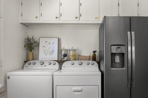 A kitchen with a stainless steel refrigerator, two Whirlpool washers, and a framed botanical print on the wall. - Dog-Friendly Arvada Home with Fire Pit, 18 Min to Red Rocks & Near Denver (Arvada)
