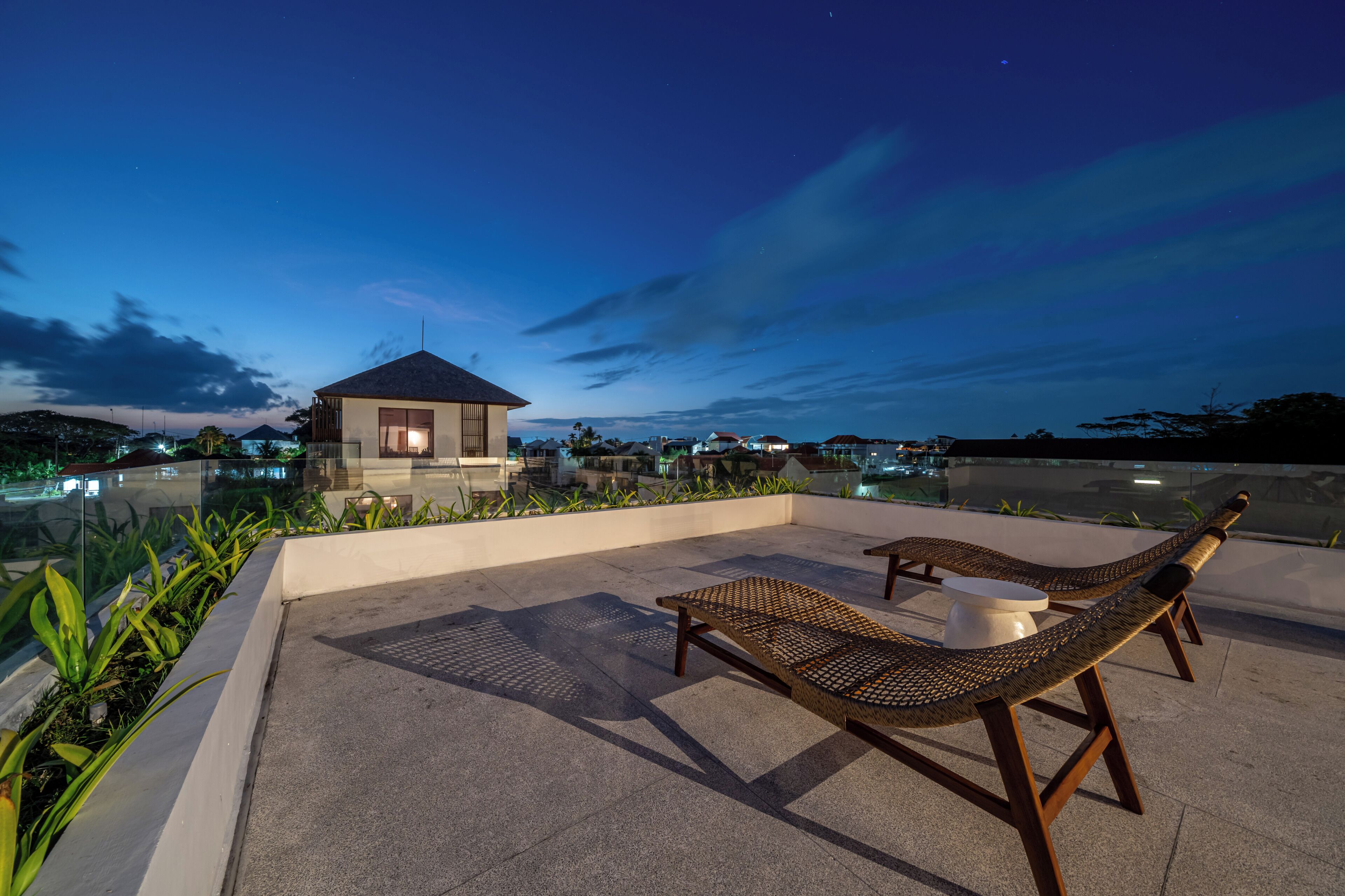 Una terraza en la azotea con sillones de descanso y un edificio pequeño.