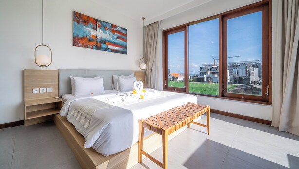 Une chambre d’hôtel moderne avec un grand lit, une table de chevet et une vue sur la ville grâce à une grande fenêtre.