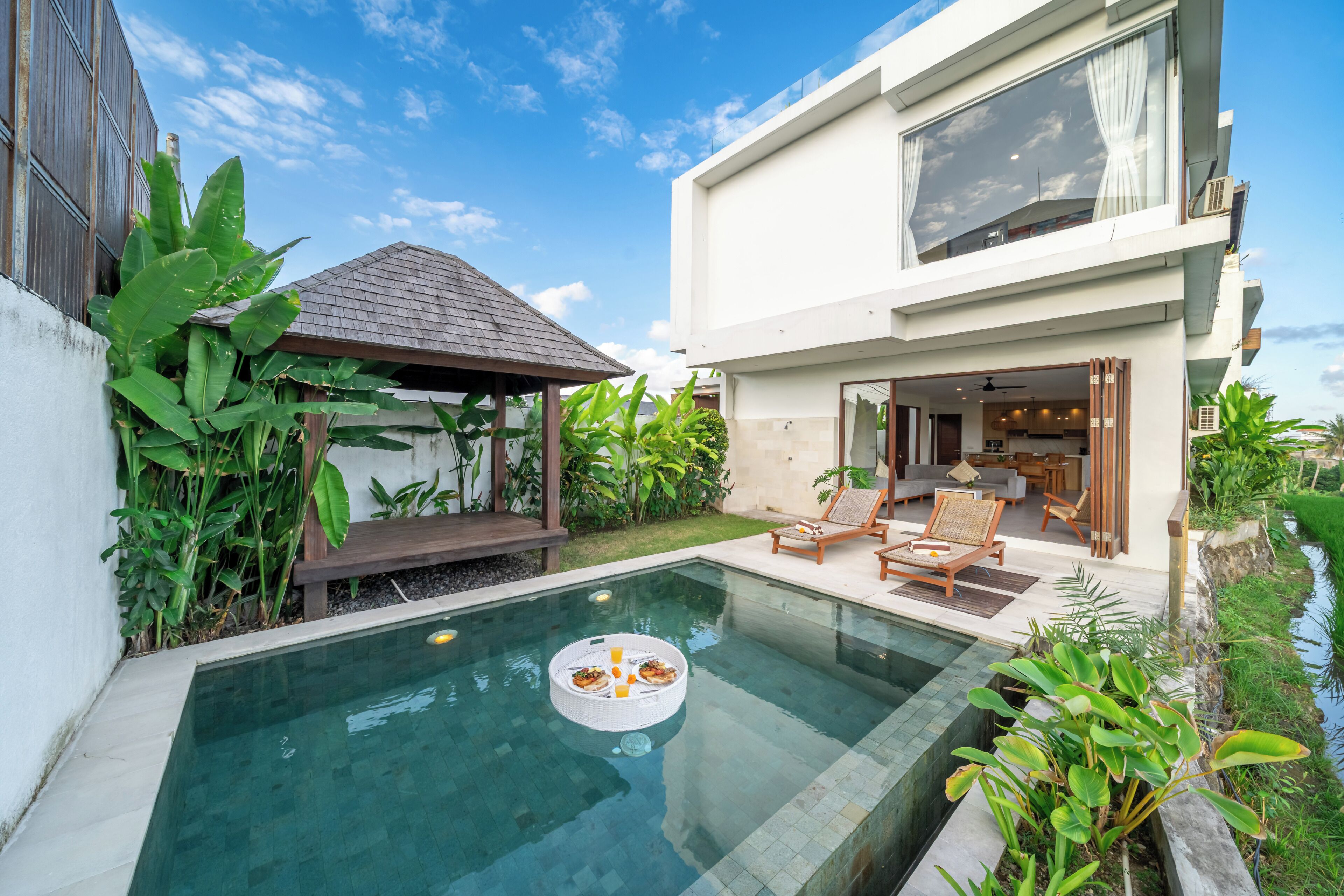 Une maison moderne dotée d’une piscine, d’un espace salon extérieur abrité et d’un jardin bien entretenu.