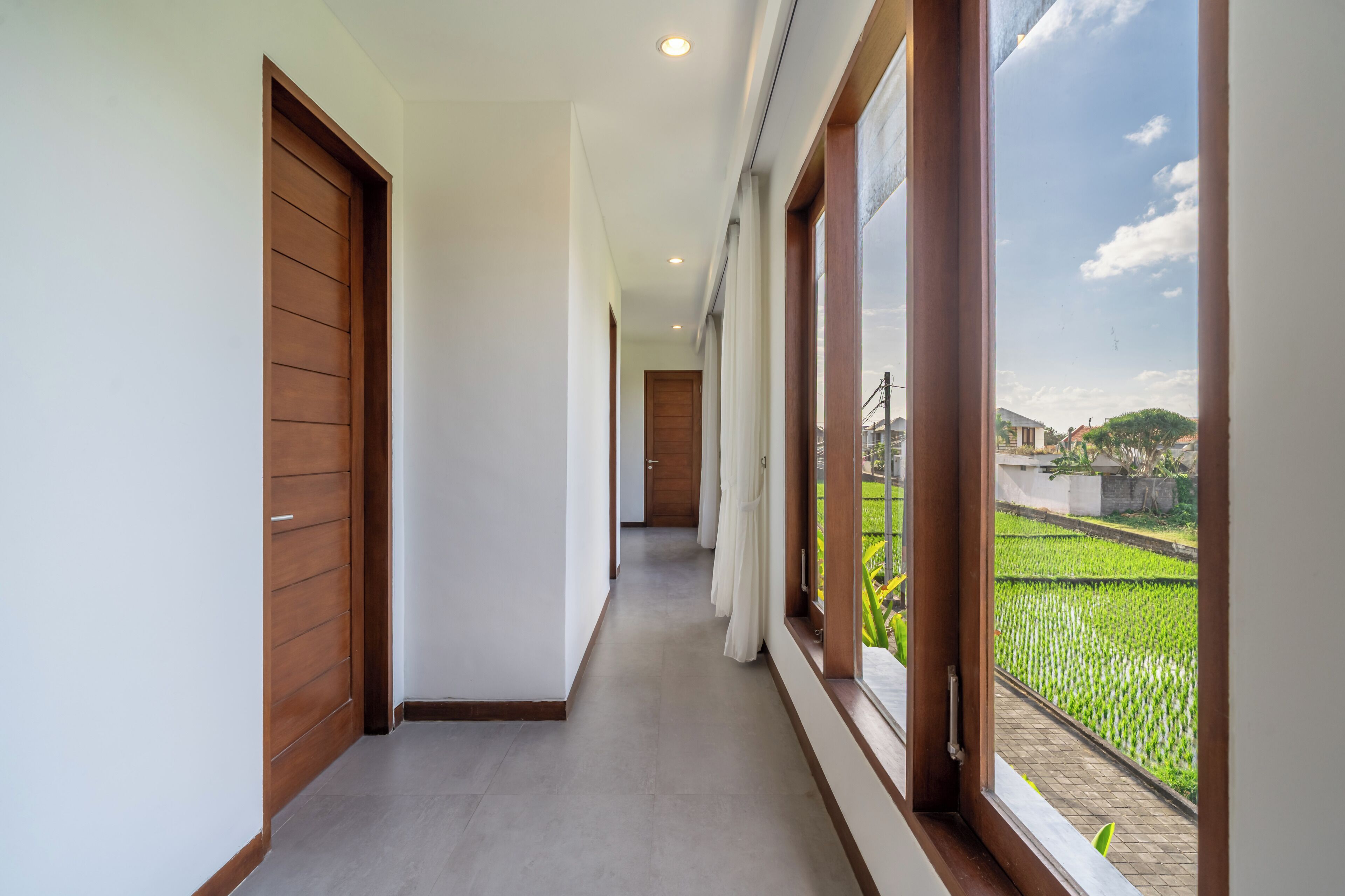 A corridor with wooden doors and large windows.