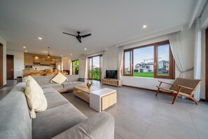 Una sala de estar moderna con un sofá, una mesa de centro y un televisor. Cuenta con un balcón con vistas a la ciudad.