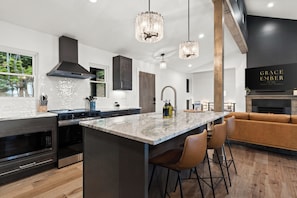 A modern kitchen with a central island, stainless steel appliances, and pendant lighting. - Modern Luxury-Couples Retreat-Hot Tub-Private Gym-Speakeasy-Close to Downtown (Blue Ridge)