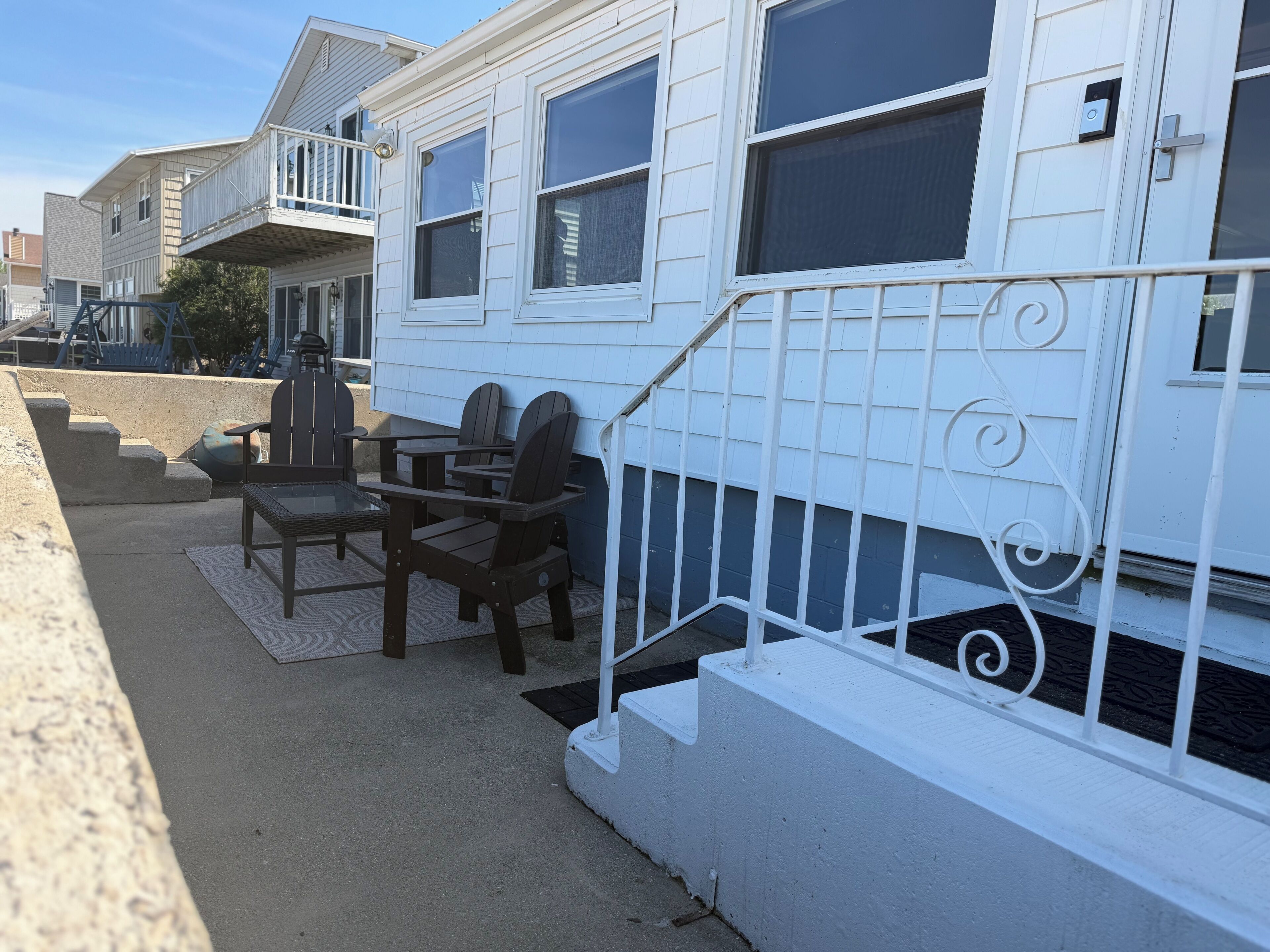 A residential building with a porch area featuring outdoor furniture.