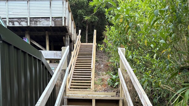 Eine hölzerne Treppe mit Metallgeländern, die zu einem Gebäude führt.