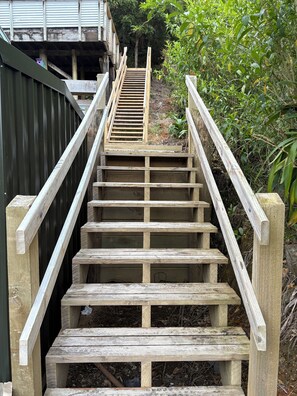A wooden staircase with metal handrails, leading up to a building.