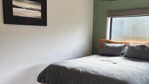 Ein Schlafzimmer mit einem hölzernen Bett, einem gerahmten Bild an der Wand und einem Fenster mit Blick.