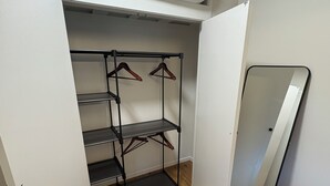 Ein kleines Zimmer mit einem Etagenbett, einem Metallschrank mit vielen Ablagen und einem großen Spiegel.