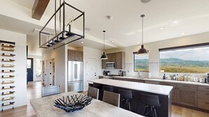 A modern kitchen with a large island, stainless steel appliances, and a view of the countryside. - Spacious 4BR retreat with hot tub, game room, and great location (Steamboat Springs)
