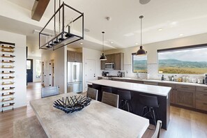 A modern kitchen with a large island, stainless steel appliances, and a view of the countryside. - Spacious 4BR retreat with hot tub, game room, and great location (Steamboat Springs)