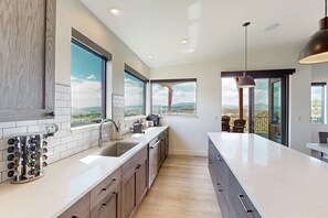 A modern kitchen with a large window, a built-in wine rack, and a view of the landscape. - Sunlight home with private hot tub, game room and EV charger (Steamboat Springs)