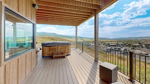 A wooden deck with a hot tub and a view of a town and hills. - Spacious 4BR retreat with hot tub, game room, and great location (Steamboat Springs)