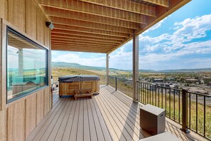 A wooden deck with a hot tub and a view of a town and hills. - Spacious 4BR retreat with hot tub, game room, and great location (Steamboat Springs)
