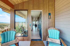 A corridor leading to a room with a view of a landscape. There are two chairs with cushions labeled 'Sunlight Sanctuary Steamboat Springs.' - Sunlight Sanctuary | Spacious retreat with hot tub, game room, and a prime location (Steamboat Springs)