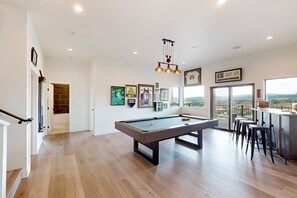 A spacious room with a pool table, framed sports memorabilia, and a view through large windows. - Sunlight Sanctuary | Spacious retreat with hot tub, game room, and a prime location (Steamboat Springs)