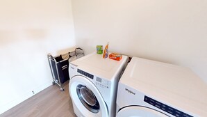 A laundry area with a front-loading Whirlpool washer and dryer, a metal drying rack, and a box of Bounce detergent. - Spacious 4BR retreat with hot tub, game room, and great location (Steamboat Springs)