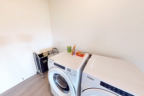 A laundry area with a front-loading Whirlpool washer and dryer, a metal drying rack, and a box of Bounce detergent. - Spacious 4BR retreat with hot tub, game room, and great location (Steamboat Springs)