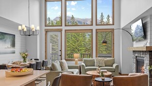 A modern interior with a dining area, seating, and a fireplace. - Spring Creek Vacations 4 BR Villa TMV18 (Canmore)