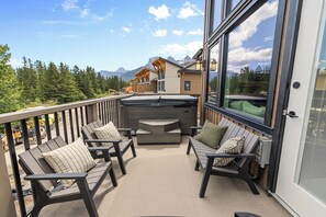 A balcony with outdoor seating, a hot tub, and a mountain view. - Spring Creek Vacations 4 BR Villa TMV24 (Canmore)
