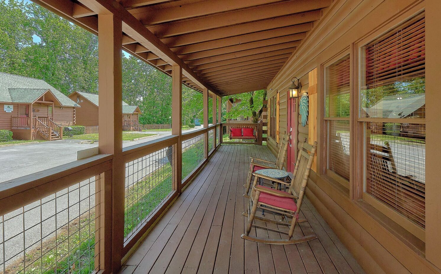 Eine hölzerne Veranda mit Geländer, Schaukelstühlen und Blick auf eine Wohngegend.