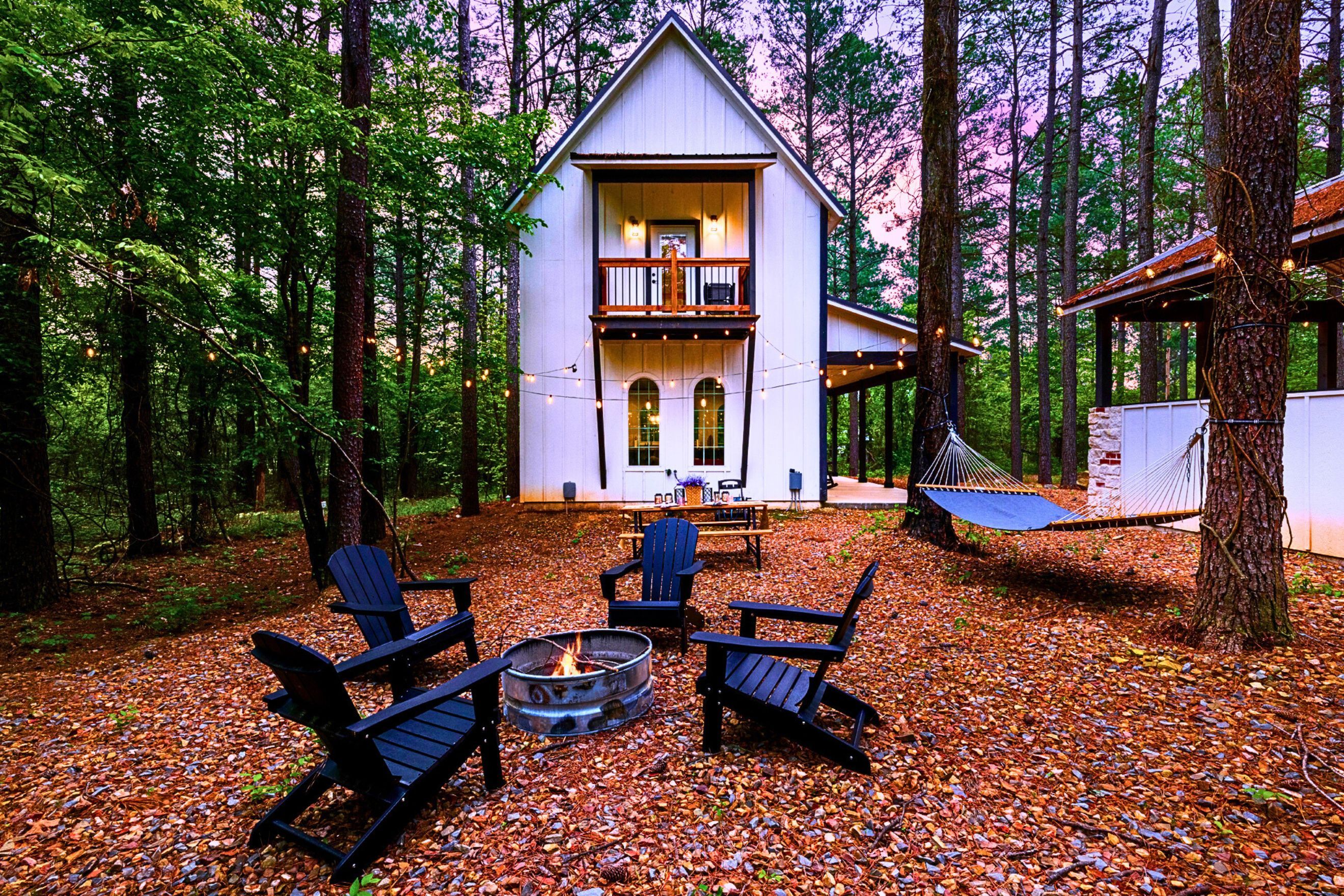 A cabin with a fire pit, outdoor seating, and a hammock.