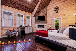 L’intérieur chaleureux d’un chalet comprend un lit, une cheminée, un téléviseur et un coin repas.