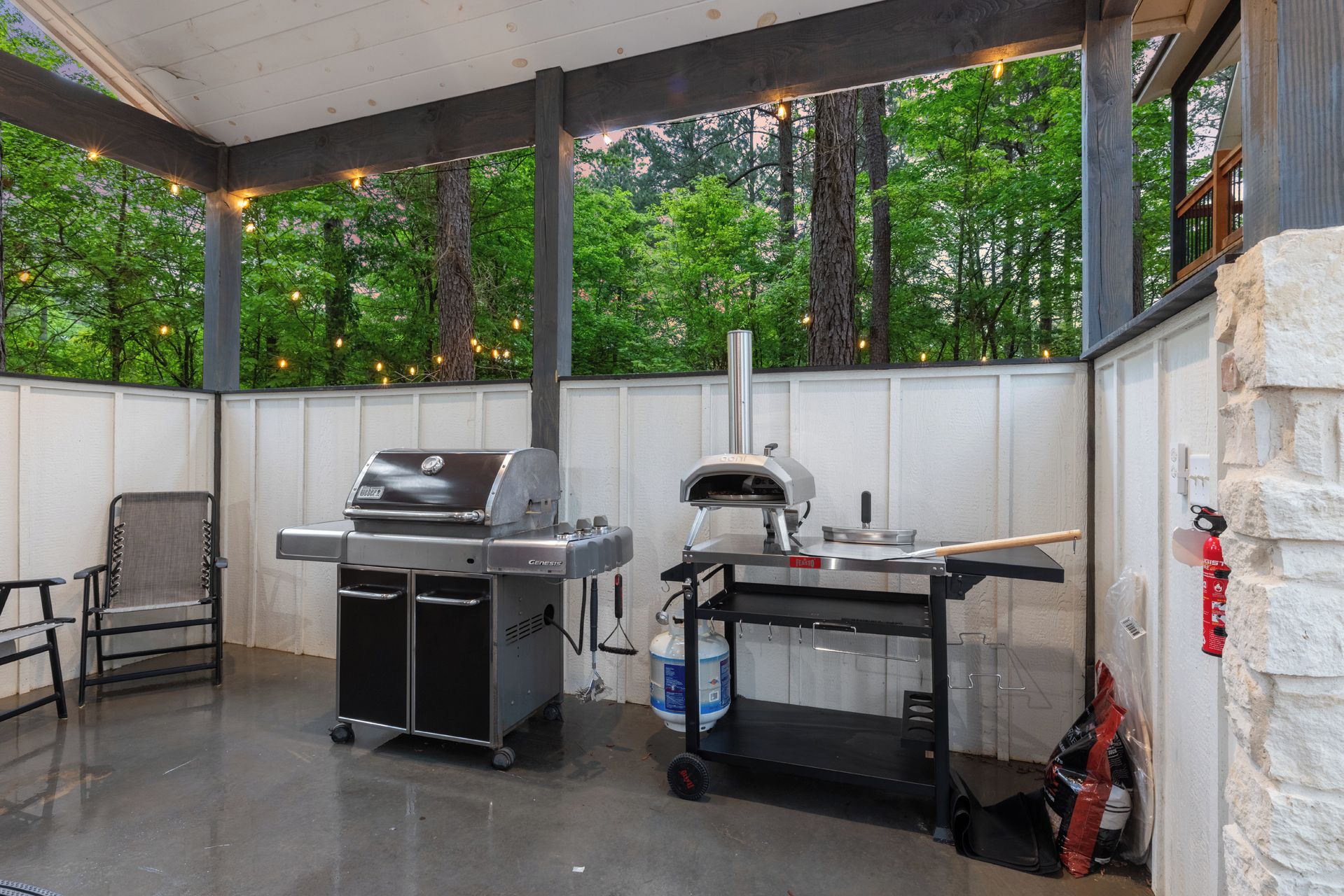 An outdoor patio area with a grill, pizza oven, and seating.