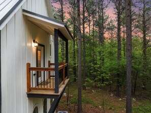 A wooden deck with a railing, a door, and a light fixture. - Romantic Cabin Getaway Sauna, Hot tub & Pizza Oven (Broken Bow)