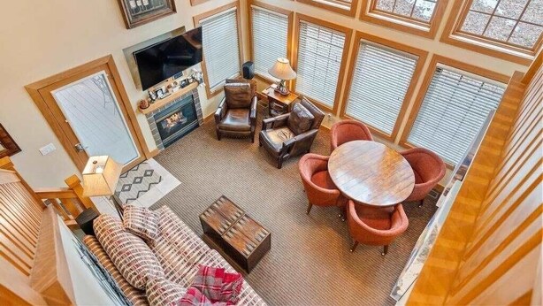 Un salon spacieux avec de hauts plafonds, une cheminée, des meubles en cuir et de grandes fenêtres.