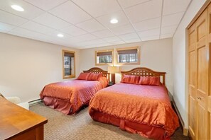 A hotel room with two beds, a desk, and a wardrobe.