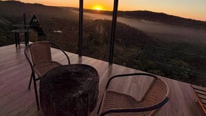 Un espacio de estar al aire libre con vista a una puesta de sol sobre un paisaje montañoso.