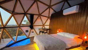 Una habitación con un diseño geométrico en el techo, una cama, una mesita y vistas al exterior.