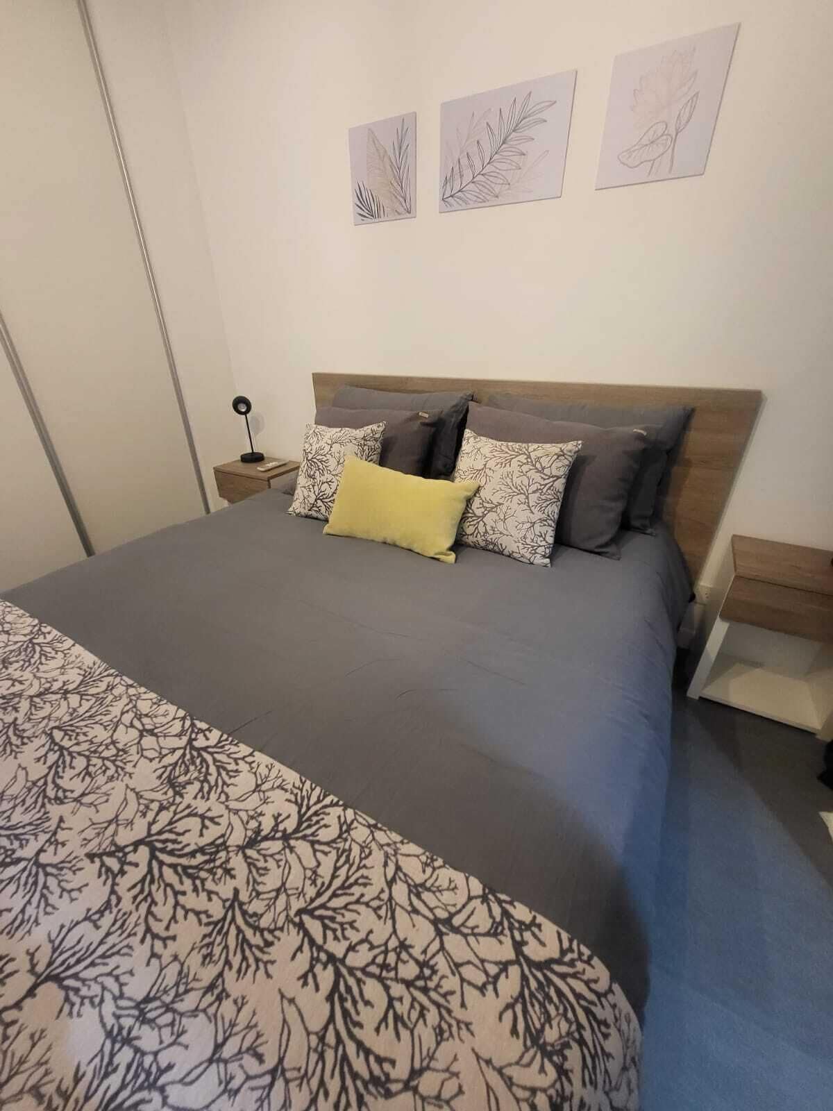 A neatly made bed with a patterned bedspread, a wooden headboard, and multiple pillows.