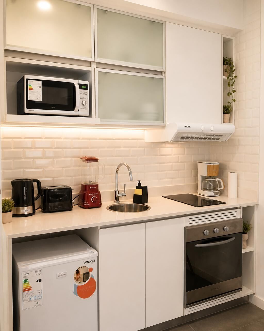 Cocina compacta equipada con microondas, tostadora, licuadora, cafetera, pileta y horno.