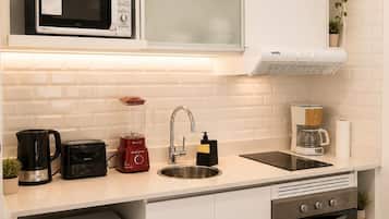Cocina compacta equipada con microondas, tostadora, licuadora, cafetera, pileta y horno.