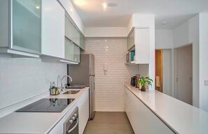 Una cocina moderna con armarios blancos, un refrigerador de acero inoxidable y un horno empotrado.