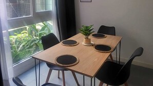 Et spiseområde med et træbord, fire sorte stole og en potteplante.