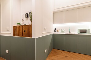 Una cocina moderna con un armario de madera, un microondas y una tetera sobre la encimera.