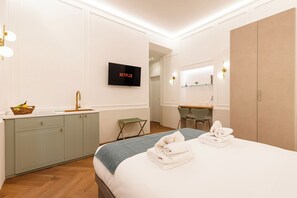 Ein Hotelzimmer mit Bett, Schreibtisch, Fernseher und Kleiderschrank.