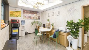A modern kitchen with a skylight, a dining area with green chairs, and a refrigerator. - Yeongdeungpo Komodo Hotel (Seoul)