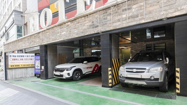 A building with two parking bays, one with a white car and another with a silver car. - Yeongdeungpo Komodo Hotel (Seoul)