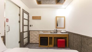A hotel room with a bed, a small desk with a mirror, a red stool, and a ceiling light fixture. - Yeongdeungpo Komodo Hotel (Seoul)