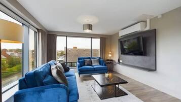 A modern living room with a sofa set, a coffee table, and a flat-screen TV mounted on the wall.