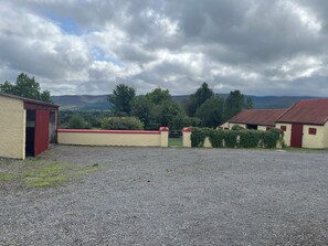 A gravel driveway leading to a building with a red door and a gate.