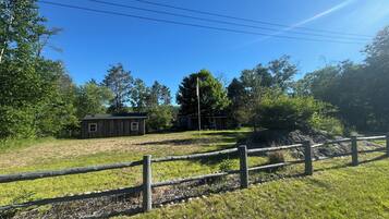A fenced property with a small wooden building, a flagpole, and a grassy area.