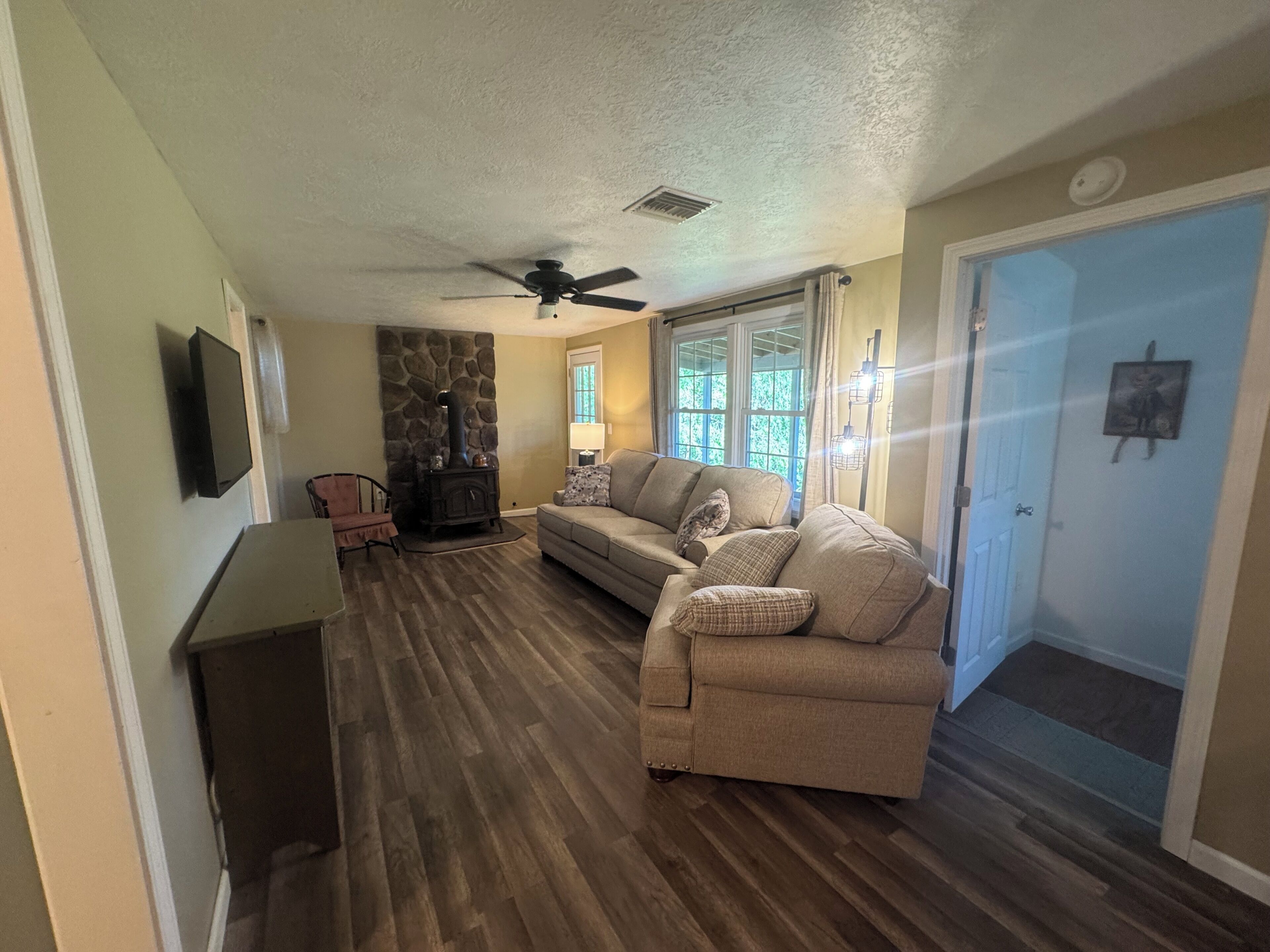 A living room with a stone fireplace, a sofa, a television, and a door.