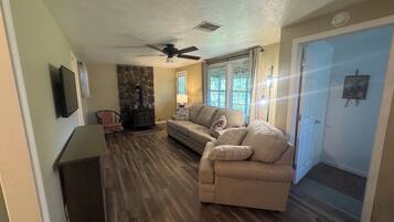 A living room with a stone fireplace, a sofa, a television, and a door.