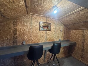 Una habitación con techo de madera, una barra y dos sillas negras.